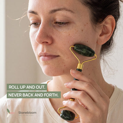 Woman using the jade facial roller on her cheek, rolling upward and outward toward the ear